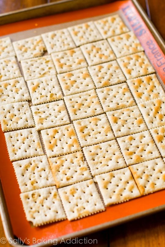 Saltine crackers on a silpat baking mat on a baking sheet