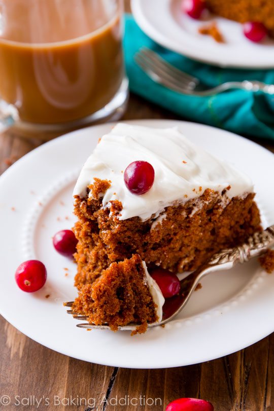 slice of gingerbread cake with cream cheese frosting on a white plate with a fork