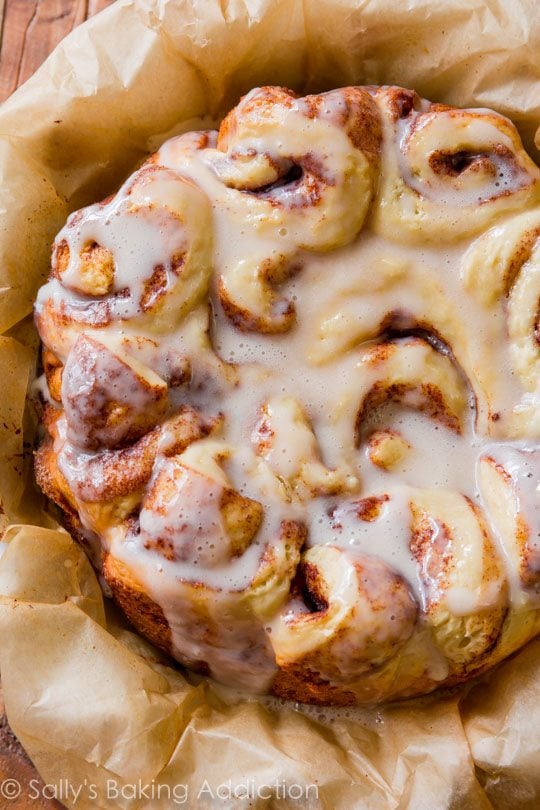 slow cooker cinnamon rolls with maple icing on parchment paper
