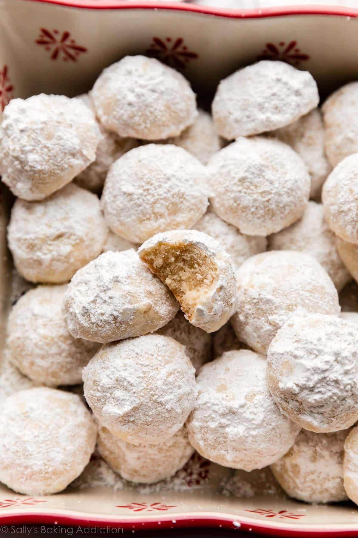 snowball cookies coated in powdered sugar in baking dish.