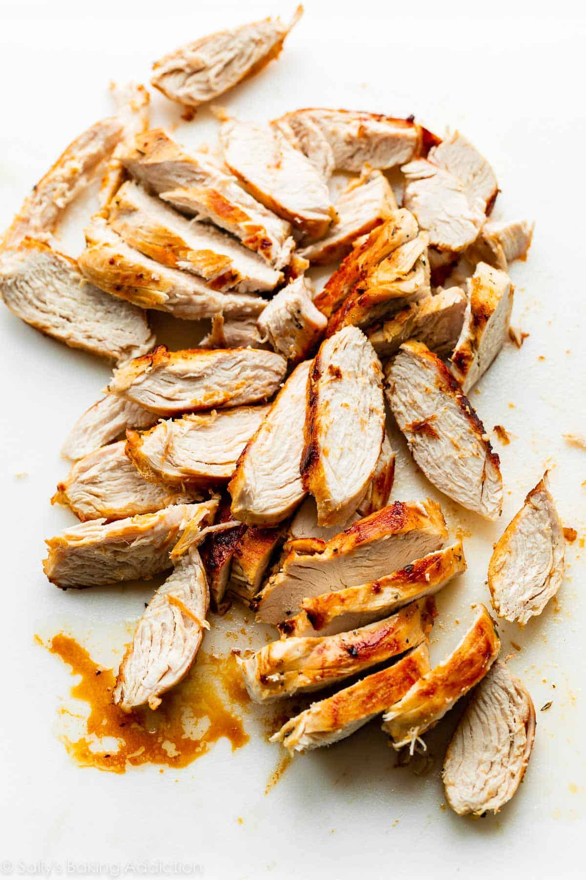 sliced cooked chicken on cutting board.