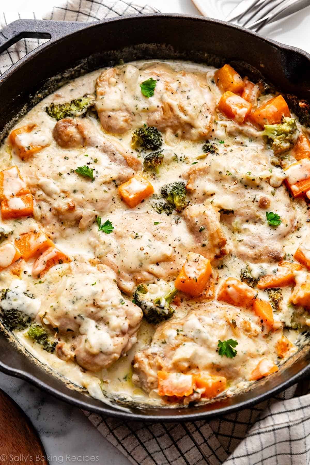 chicken, broccoli, and butternut squash in creamy garlic sauce with fresh parsley in cast iron skillet.