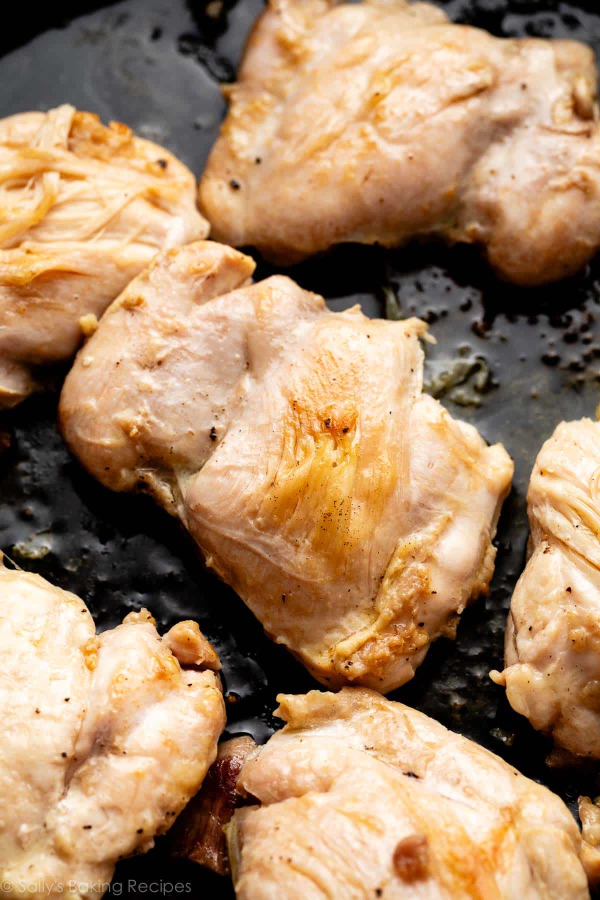 close-up of mostly cooked chicken thighs in a black cast iron skillet.