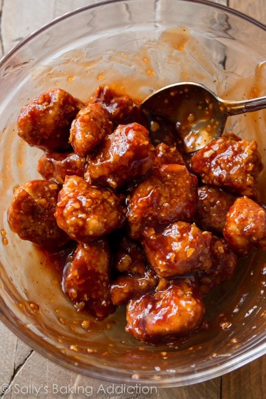 baked honey bbq popcorn chicken in a glass bowl with a spoon