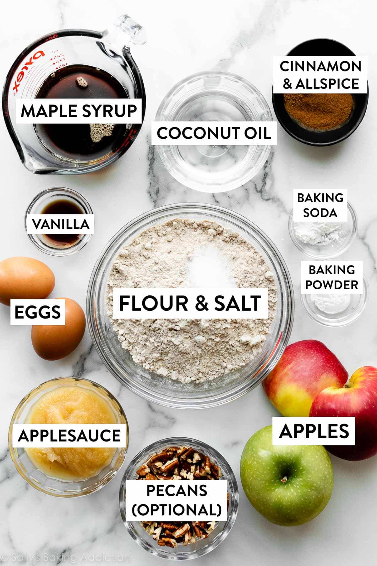 whole wheat flour, coconut oil, maple syrup, pecans, apples, and other ingredients on marble cutting board.
