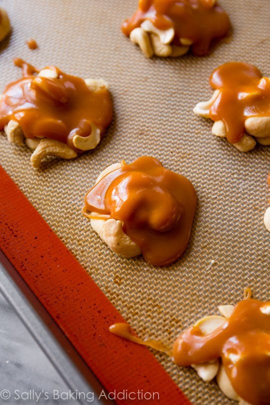 cashew clusters topped with caramel on a silpat baking mat