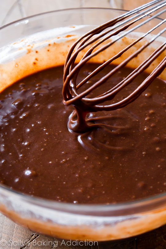 chocolate cake batter in a glass bowl with a whisk