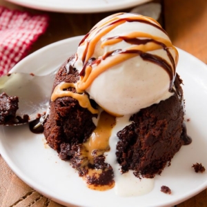 chocolate peanut butter lava cake with a scoop of ice cream on top on a white plate with a spoon