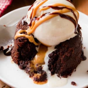 peanut butter chocolate lava cake on a white plate with a scoop of vanilla ice cream on top.
