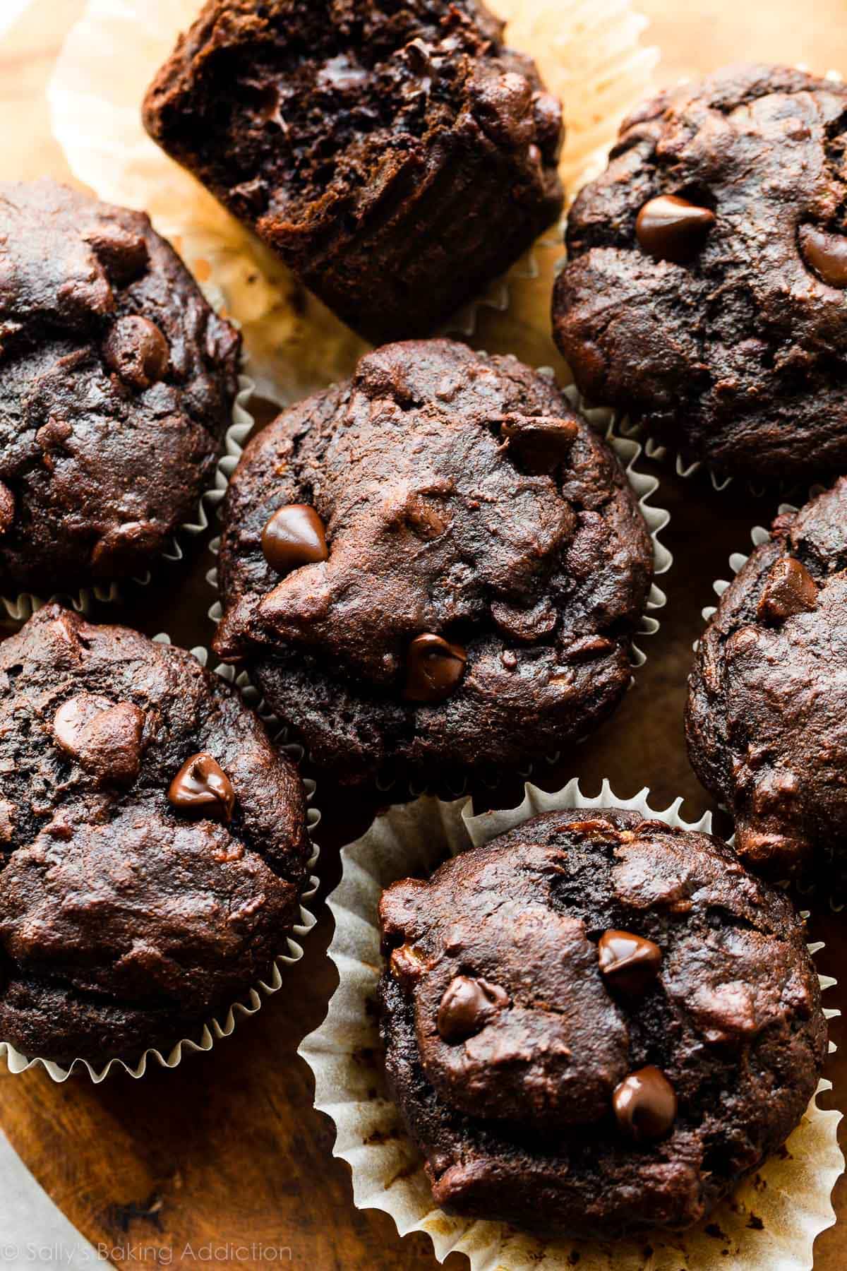 up close photo showing the tops of chocolate banana muffins on a wooden cutting board.