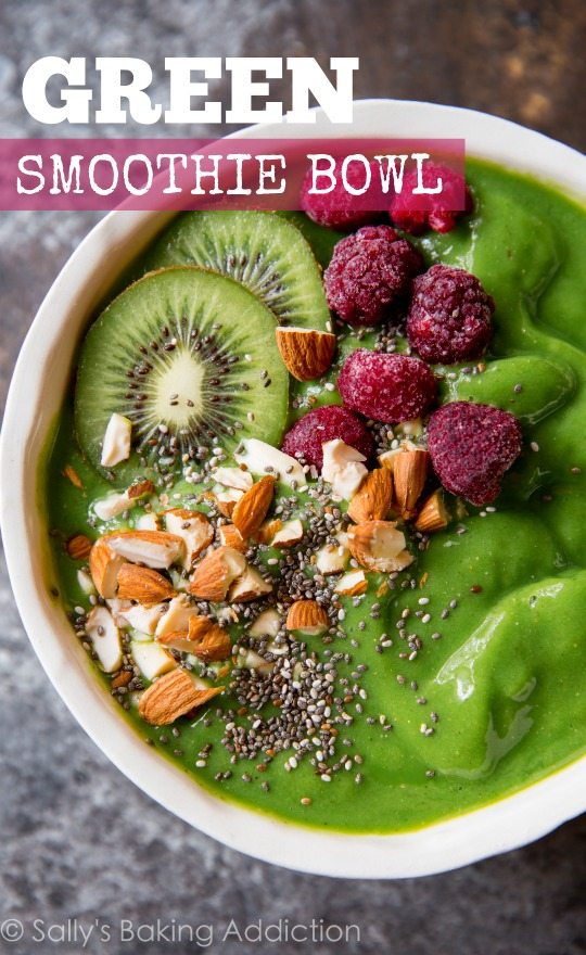 green smoothie in a bowl topped with kiwi, almonds, chia seeds, and raspberries