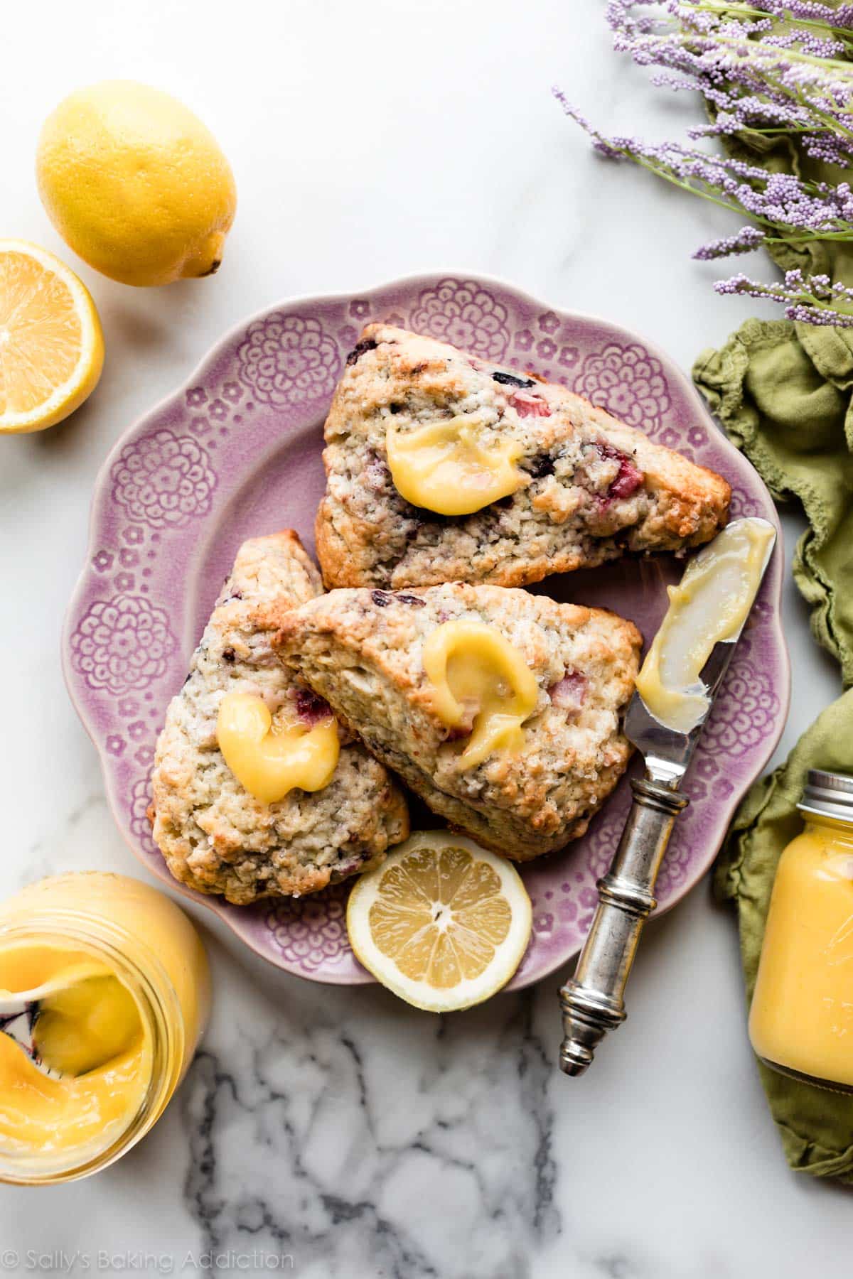 Lemon curd on mixed berry scones on a pink plate