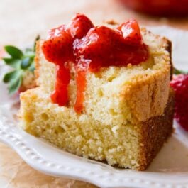 2 slices of brown butter pound cake on a white plate topped with strawberry compote