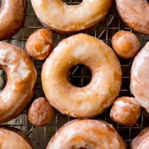 overhead image of glazed doughnuts on a cooling rack