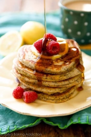 stack of lemon poppy seed pancakes with maple syrup on a cream plate