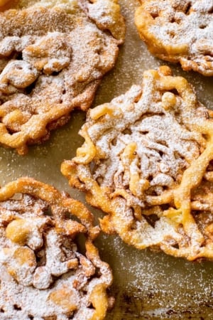 overhead image of funnel cakes topped with confectioners' sugar