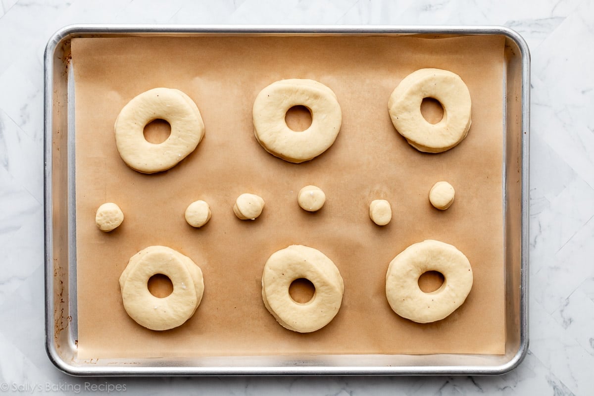 uncooked doughnuts on lined baking sheet.