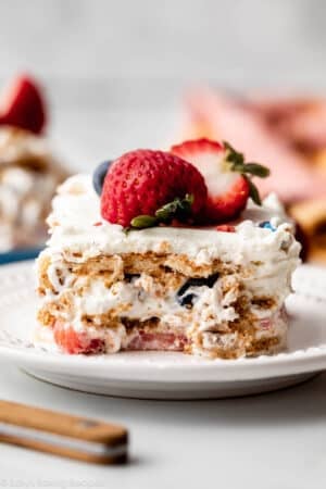 slice of berry icebox cake with vanilla whipped cream between the layers on white plate.