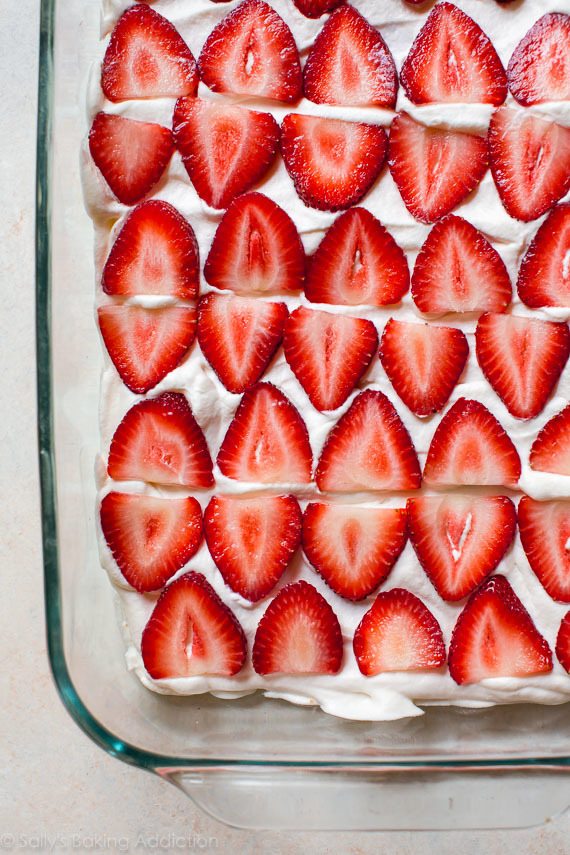 layer of sliced strawberries on top of whipped cream in a glass baking dish