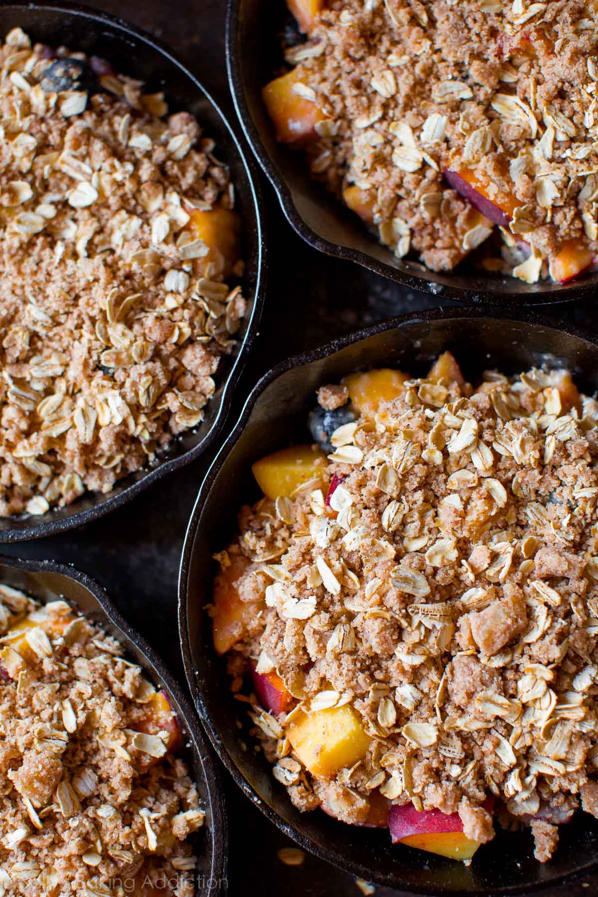 skillets with blueberry peach filling with crisp topping before baking