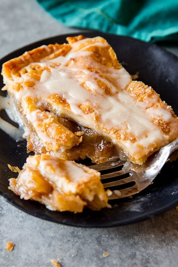 slice of apple slab pie on a black plate with a fork
