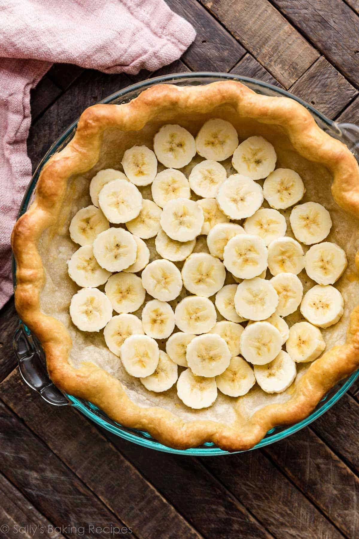 banana slices arranged in bottom of baked pie crust shell.
