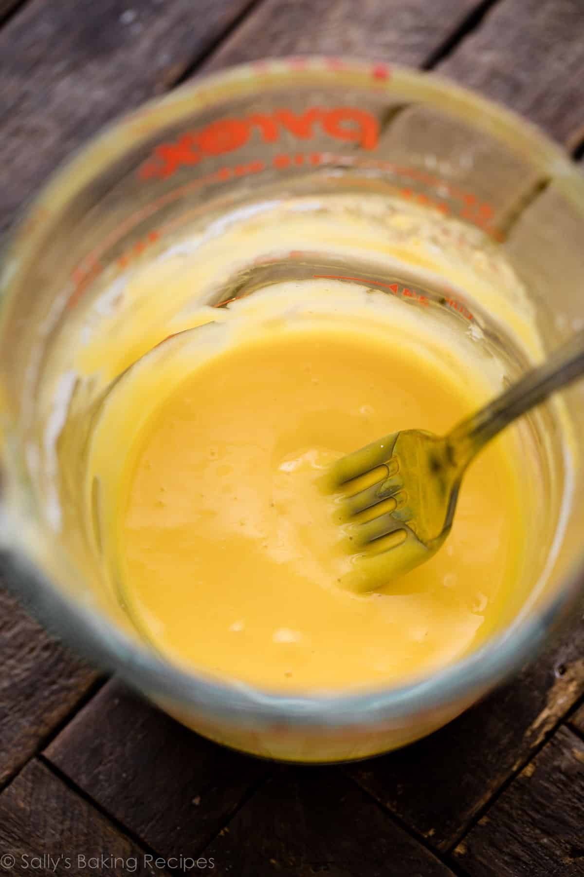 egg yolk mixture with fork inside liquid measuring cup.