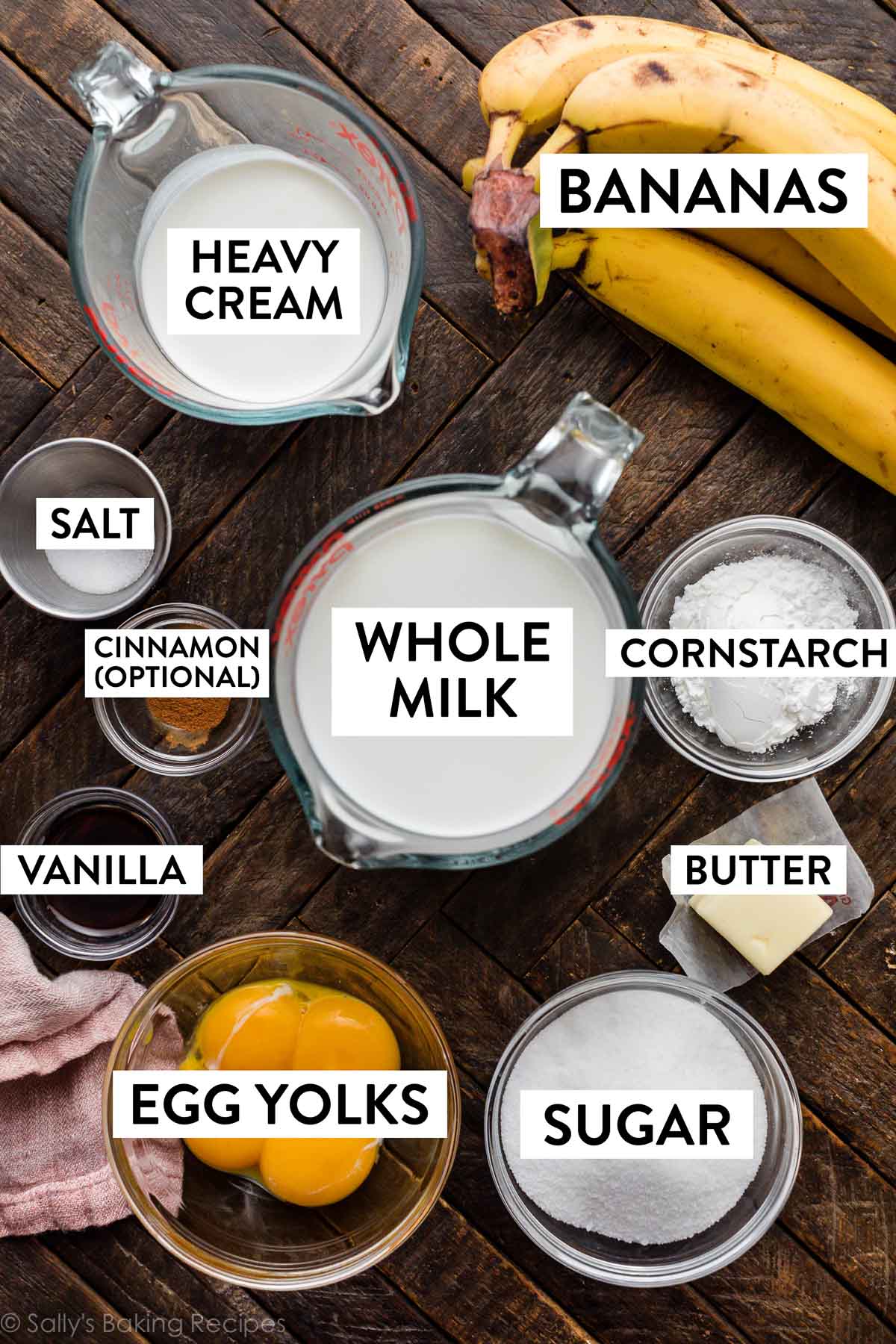 whole milk, bananas, heavy cream, egg yolks, sugar, cornstarch, and other ingredients on wooden backdrop.