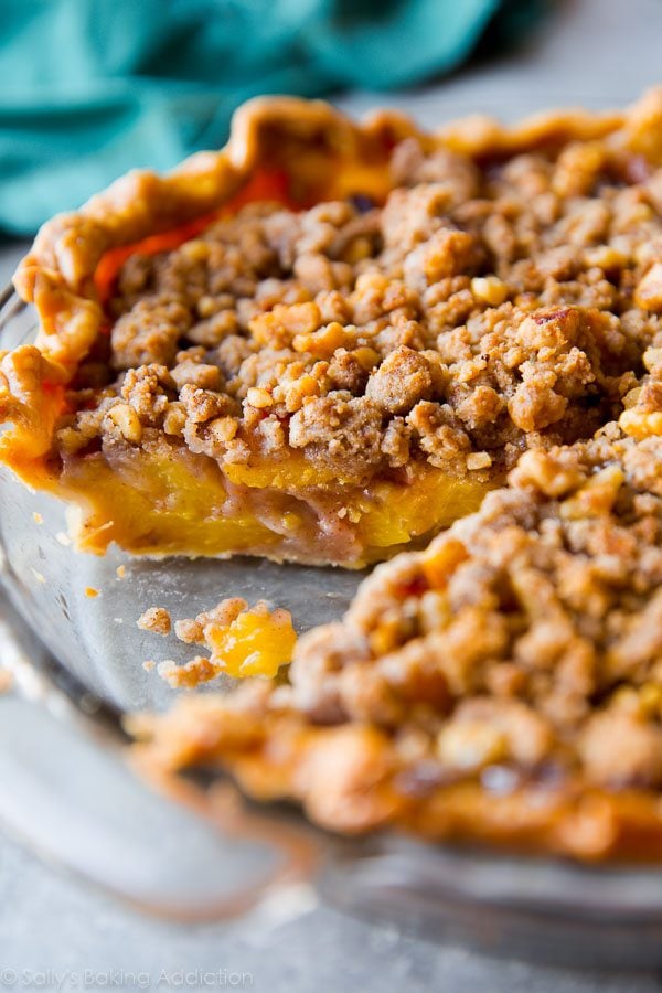 side view of peach crumble pie in a glass pie dish