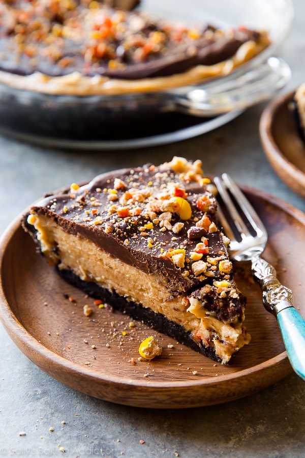 A slice of peanut butter pie on a wooden plate with a fork