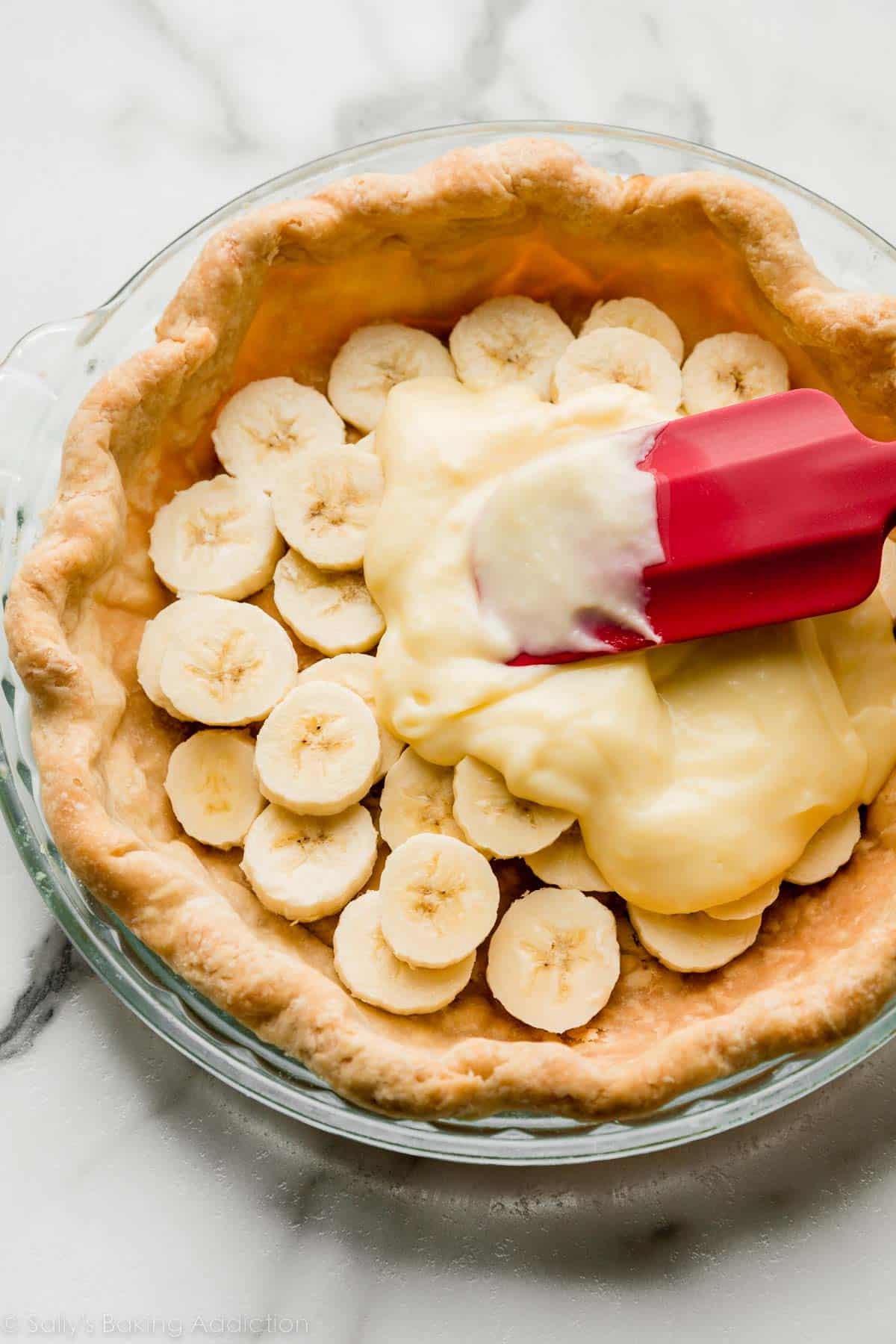 spreading pudding over bananas in a baked pie crust shell.
