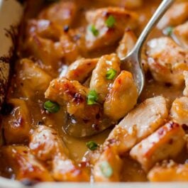 sweet chili chicken in a baking dish with a serving spoon
