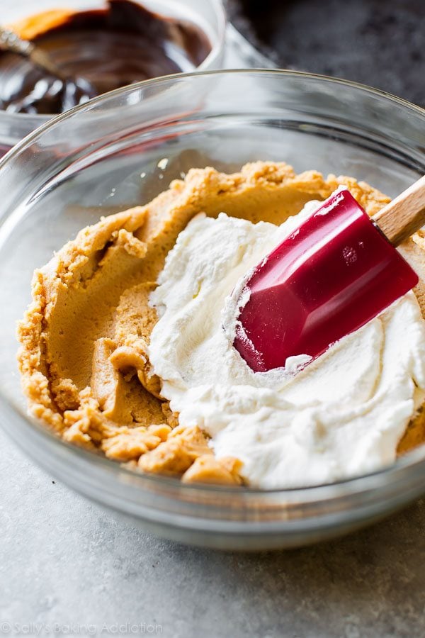 folding whipped cream into peanut butter filling in a glass bowl