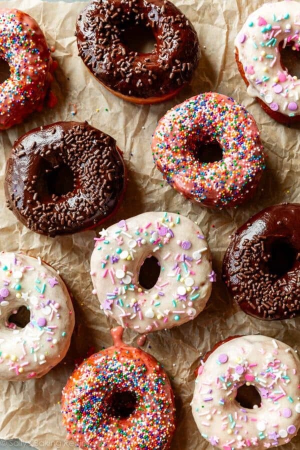 homemade doughnuts with various flavor frostings and sprinkles on top.