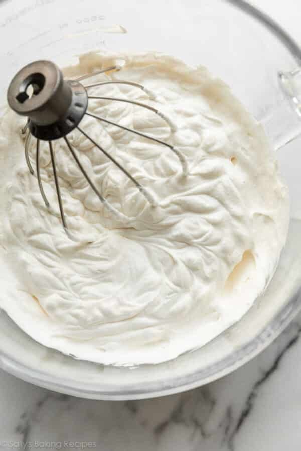 glass bowl of whipped cream with whisk attachment.