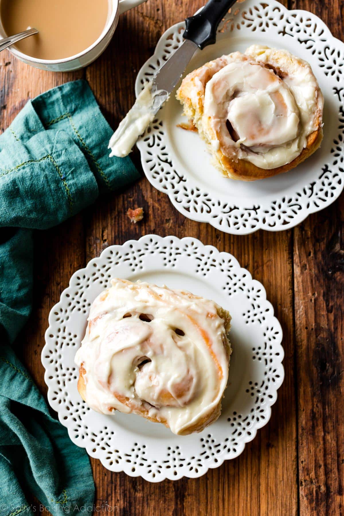 two big frosted cinnamon rolls on white plates