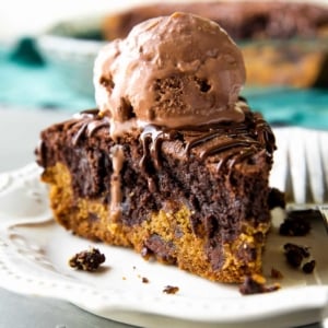 slice of brookie pie with a scoop of chocolate ice cream on top on a white plate with a fork