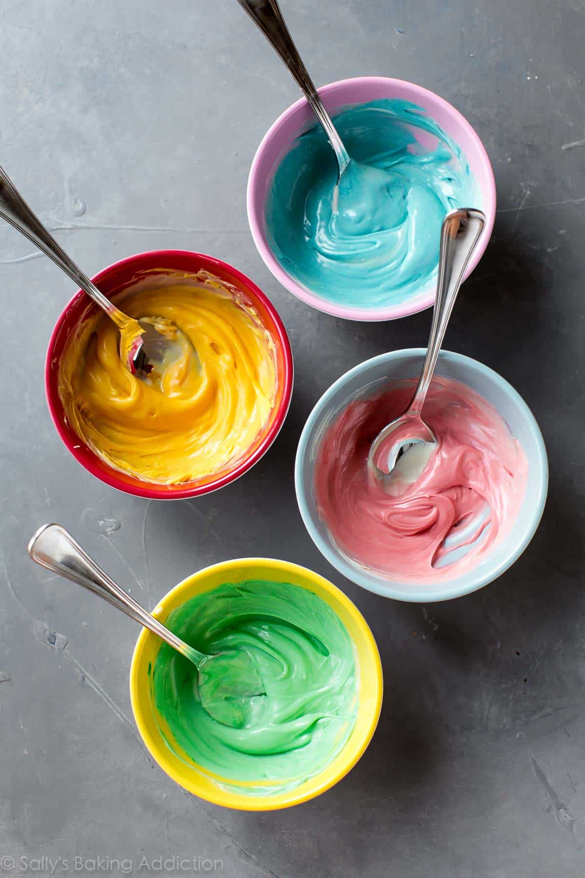 melted white chocolate in bowls tinted blue, yellow, red, and green