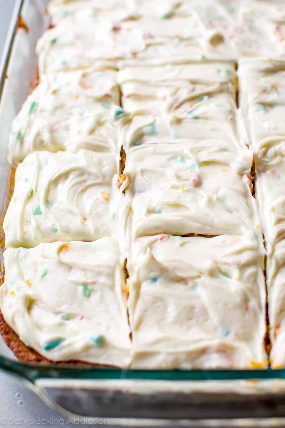 sheet cake in a glass pan with rainbow chip frosting spread on top