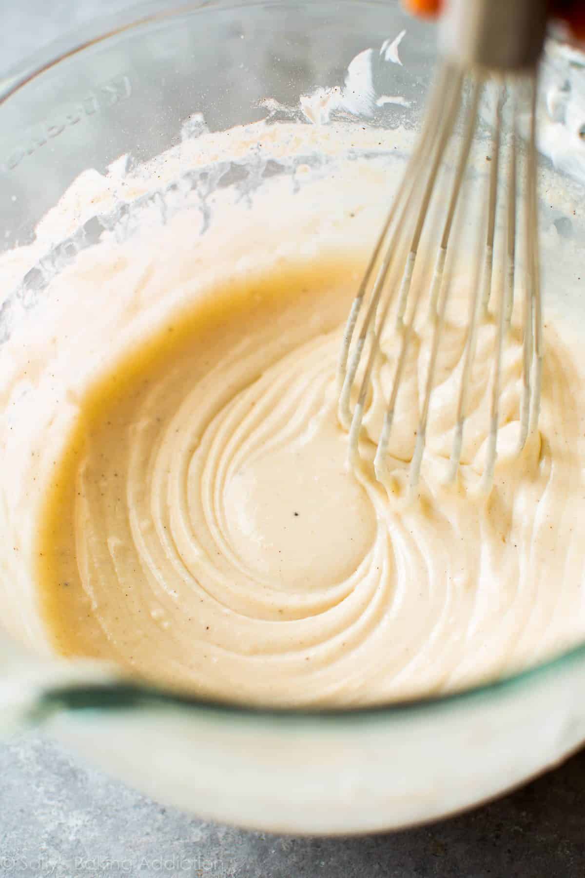 cupcake batter in a glass bowl with a metal whisk.