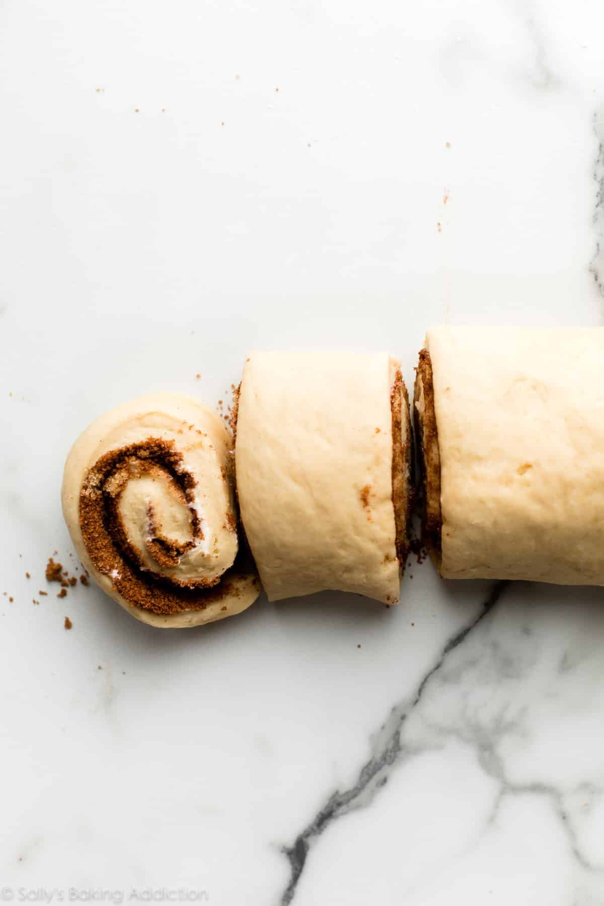 cutting cinnamon roll dough into rolls