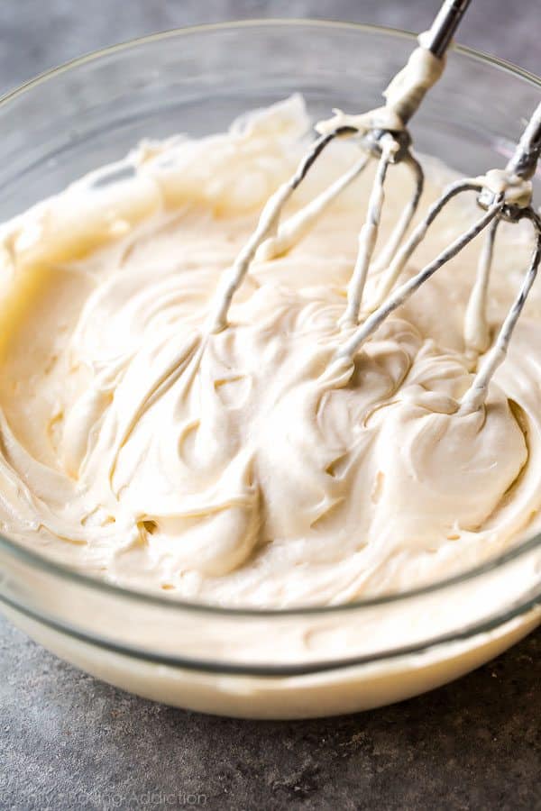 cream cheese frosting in a glass bowl with a hand mixer