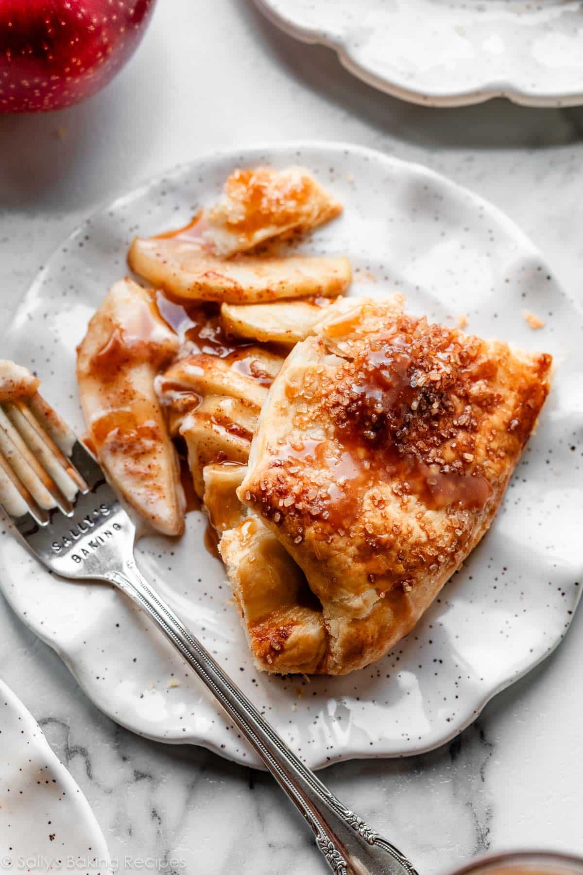 apple galette slice with caramel on white plate with fork.