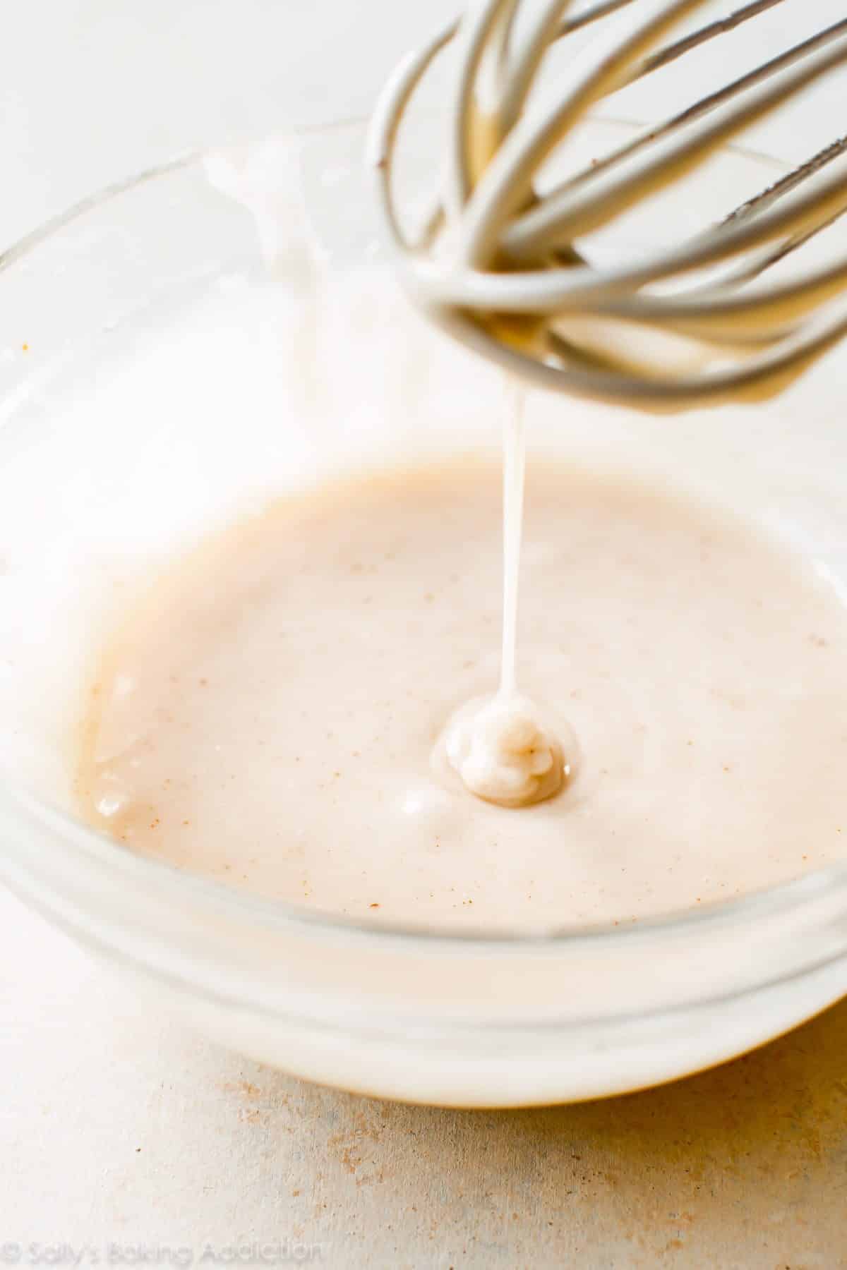 brown butter icing in a glass bowl with a whisk