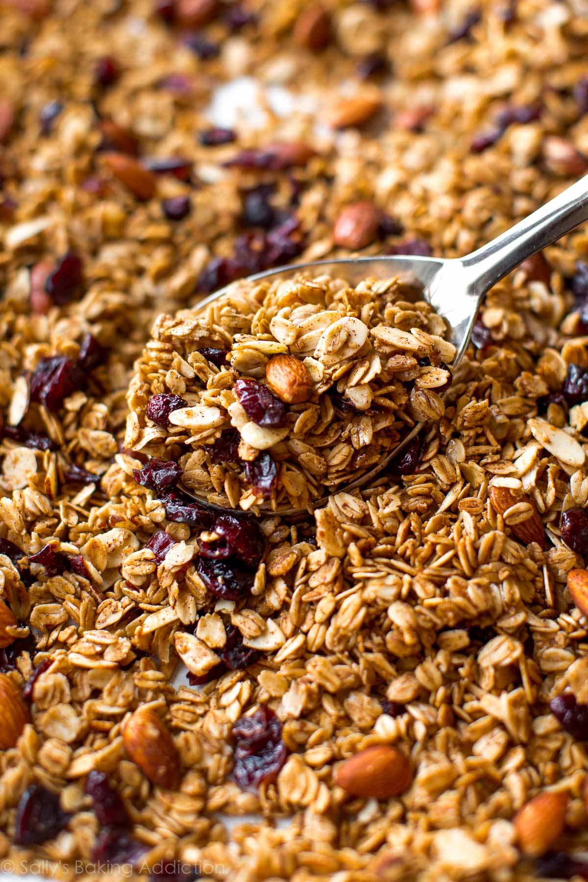 maple almond cranberry granola with a serving spoon