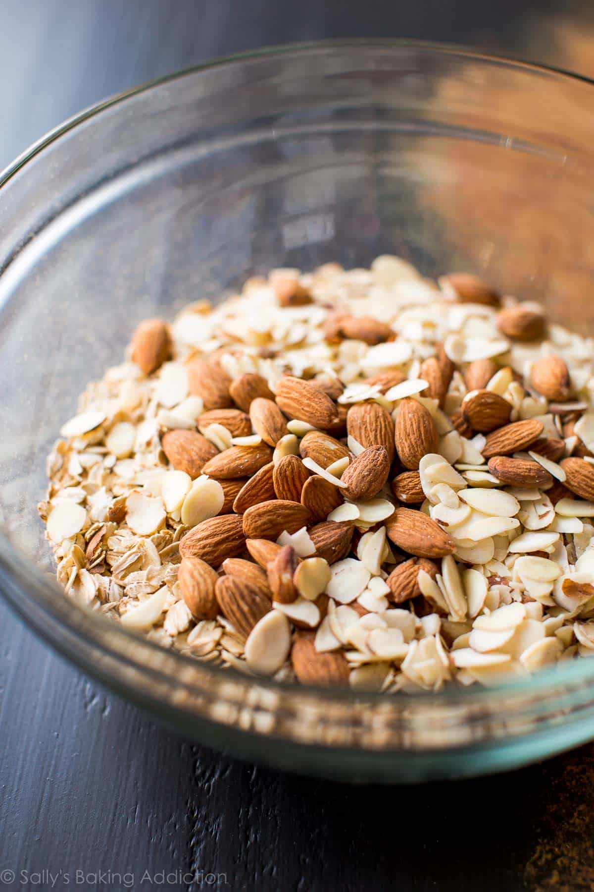 dry ingredients including oats and almonds in a glass bowl