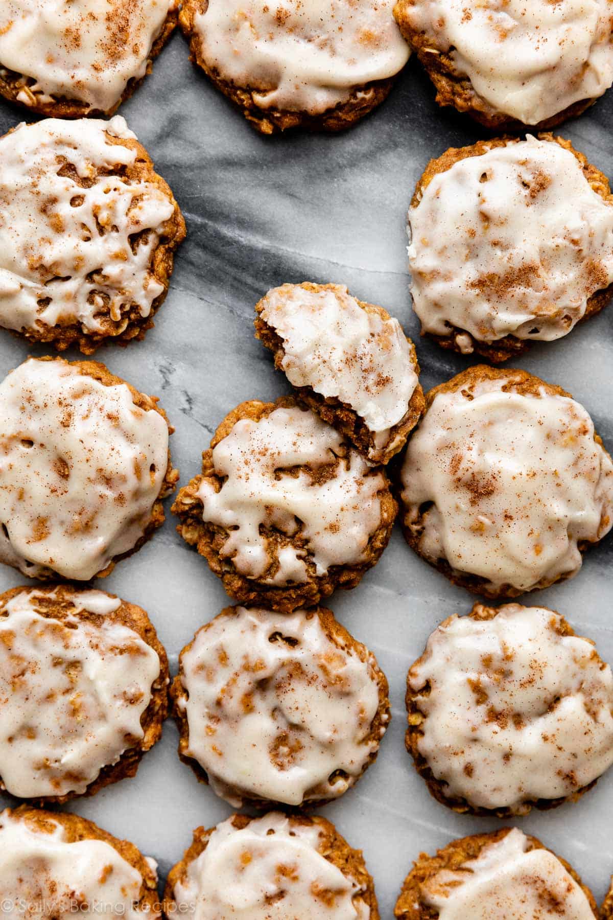 overhead photo of pumpkin oatmeal cookies with icing on marble counter.