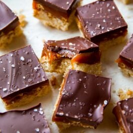 salted caramel pretzel crunch bars cut into squares with a bite taken from one bar