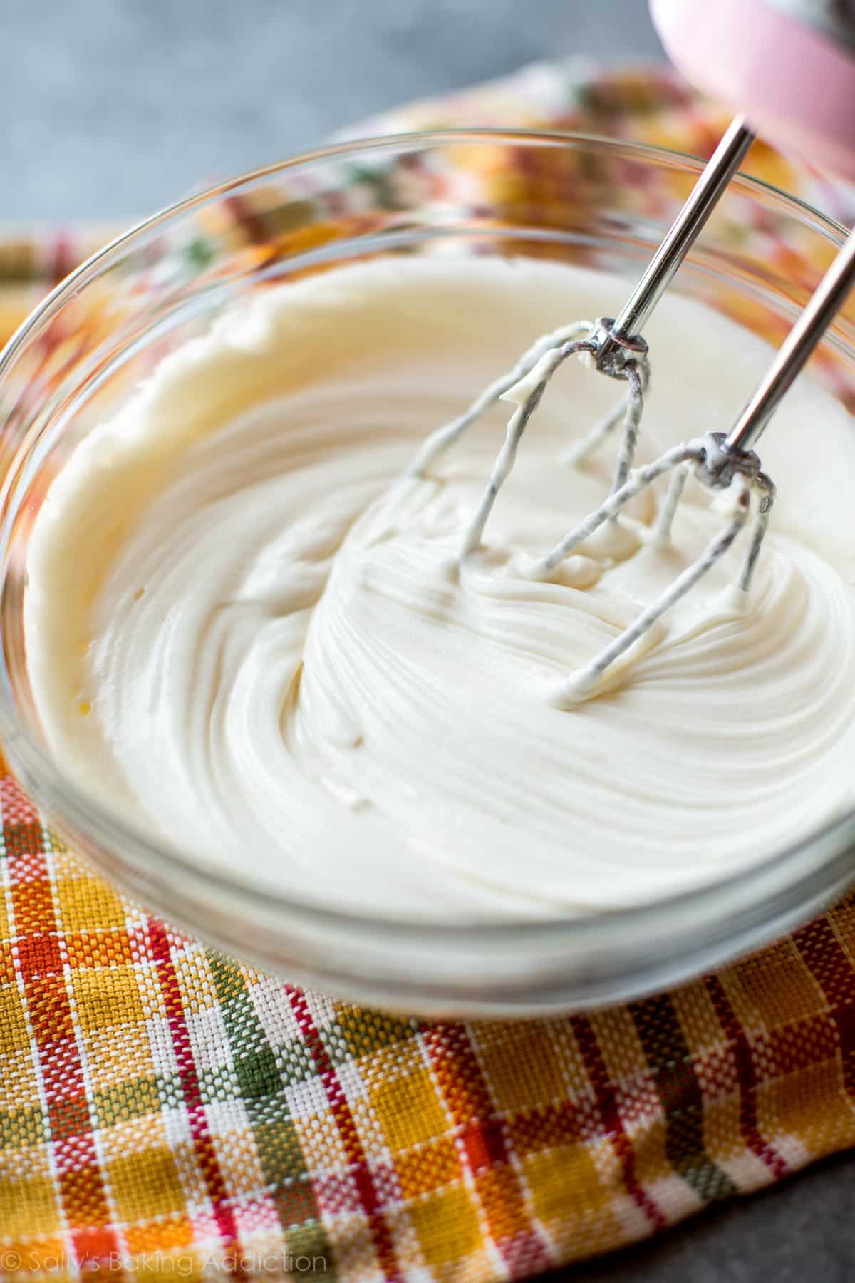 Cream cheese frosting in glass bowl with a hand mixer
