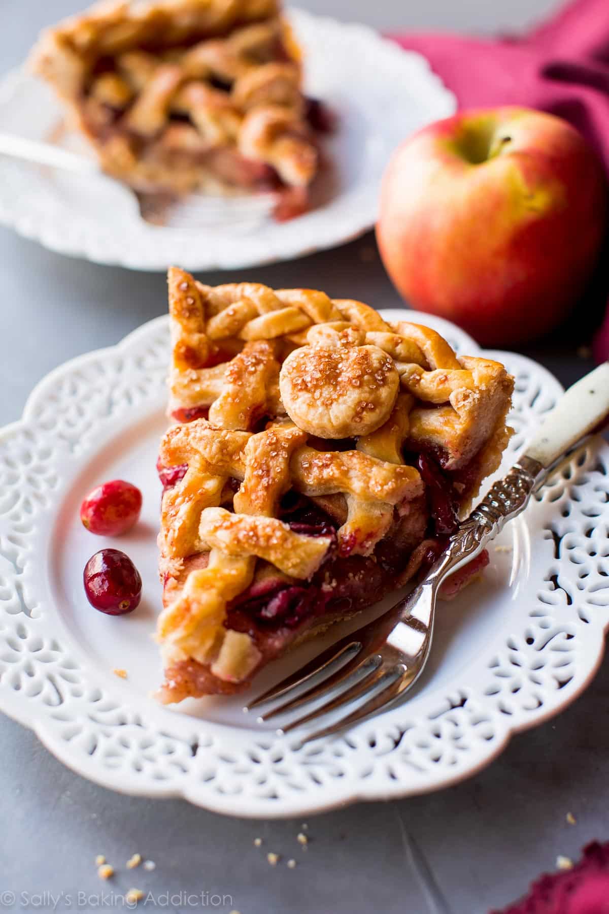 slice of apple cranberry pie on a white plate with a fork